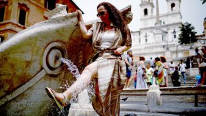 A woman cools off at the Fontana della Barcaccia at the Spanish Steps in Rome.