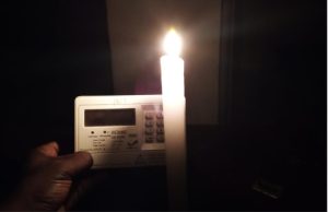 Kenya Power prepaid meter next to a burning candle. PHOTO/Martin Oduor