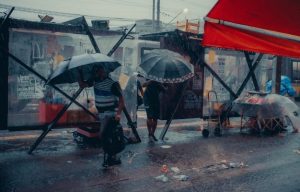 People with Umbrellas Walking on a Sidewalk in City in Heavy Rain. PHOTO/Pexels