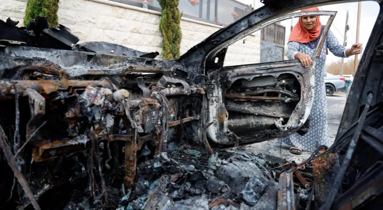 A Palestinian woman inspects a vehicle destroyed during an Israeli settler attack in the village of Jit, in the West Bank, August 16. PHOTO/Raneen Sawafta/Reuters