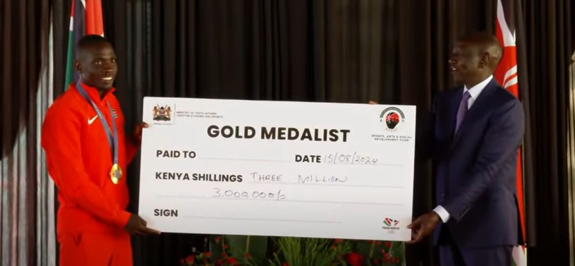 President William Ruto and athlete Emmanuel Wanyonyi holding a dummy cheque at the Eldoret State Lodge on Thursday August 15, 2025. PHOTO/Screengrab by K24 Digital