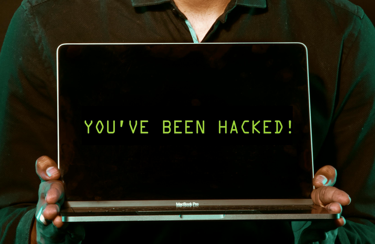 A man holds a laptop with 'You've been hcked written on it's screen. Image used for representation only. PHOTO/Pexels