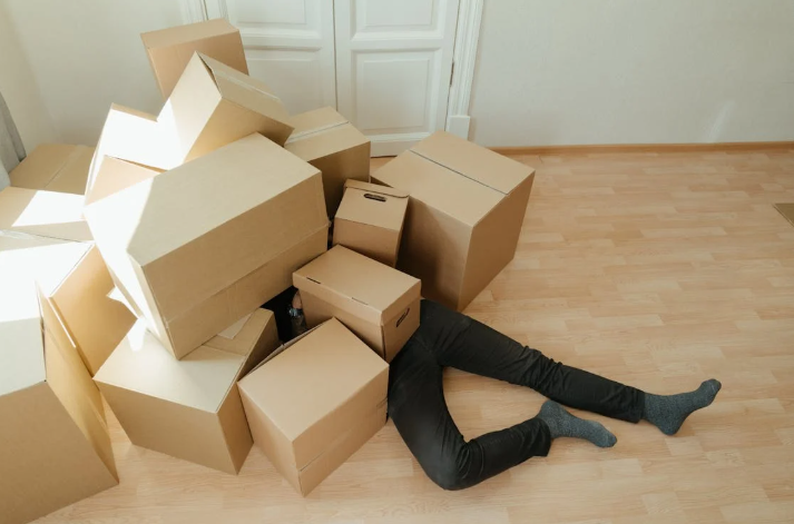 A person hides beneath a pile of packing boxes for packing household items. PHOTO/Pexels
