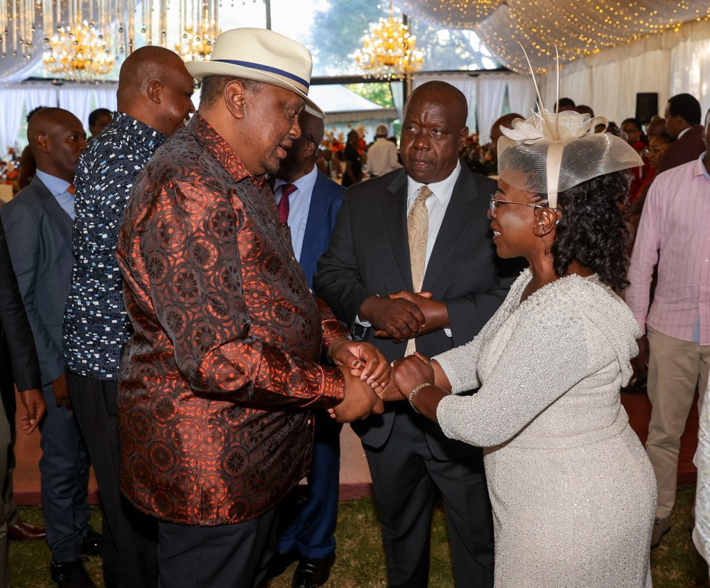 Former Interior CS Fred Matiang'i (in suit) looks on as his wife shakes hands with former President Uhuru Kenyatta. PHOTO/@4thPresidentKE/X