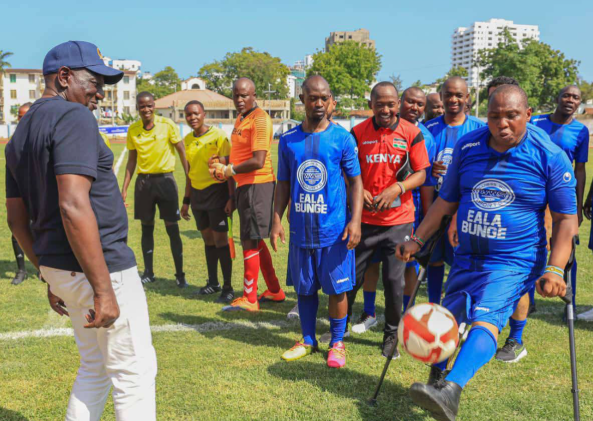East African Legislative Assembly Member of Parliament (MP) David Sankok shows off his football skills to President William Ruto (in hat) during the 2024 inter-parliamentary games in Mombasa. PHOTO/https://web.facebook.com/profile.php?id=100044397670665