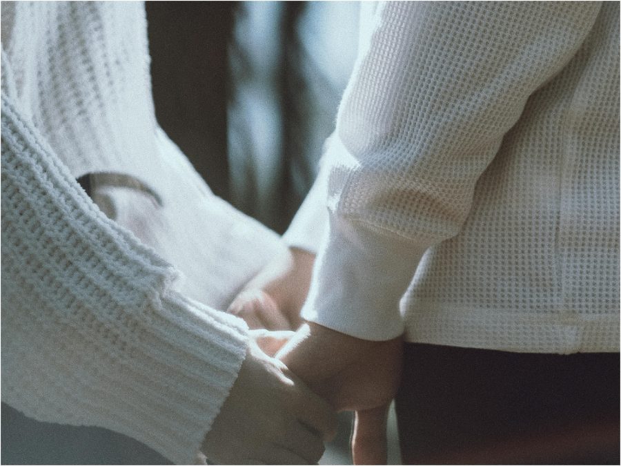 Crop stylish couple holding hands on street