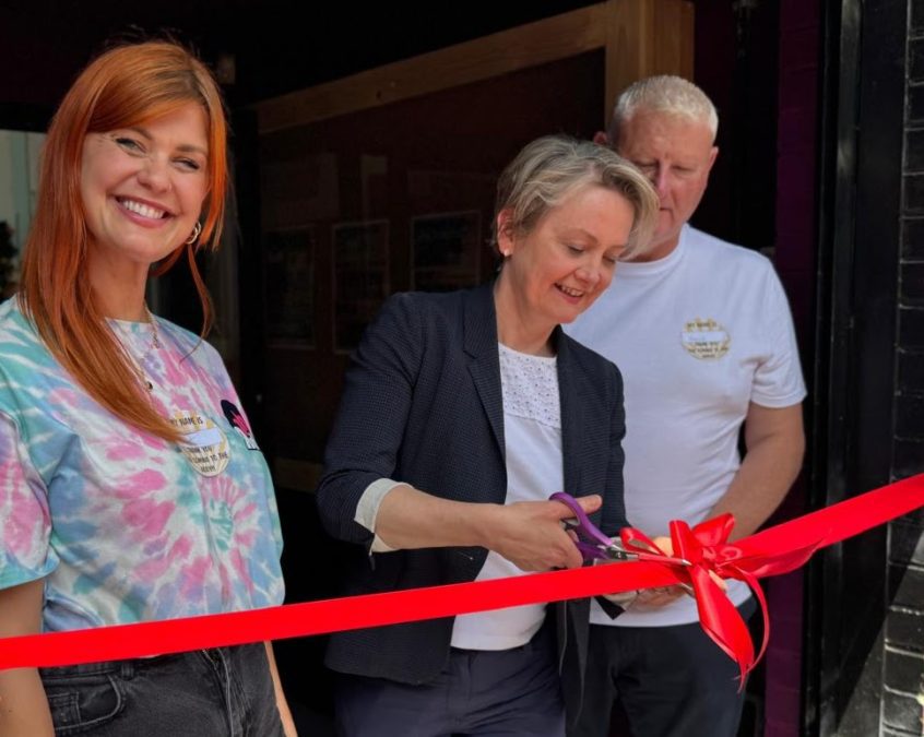 Yvette Cooper smiles as she cuts a red ribbon with scissors during an event. PHOTO/https://www.facebook.com/YvetteCooperMP