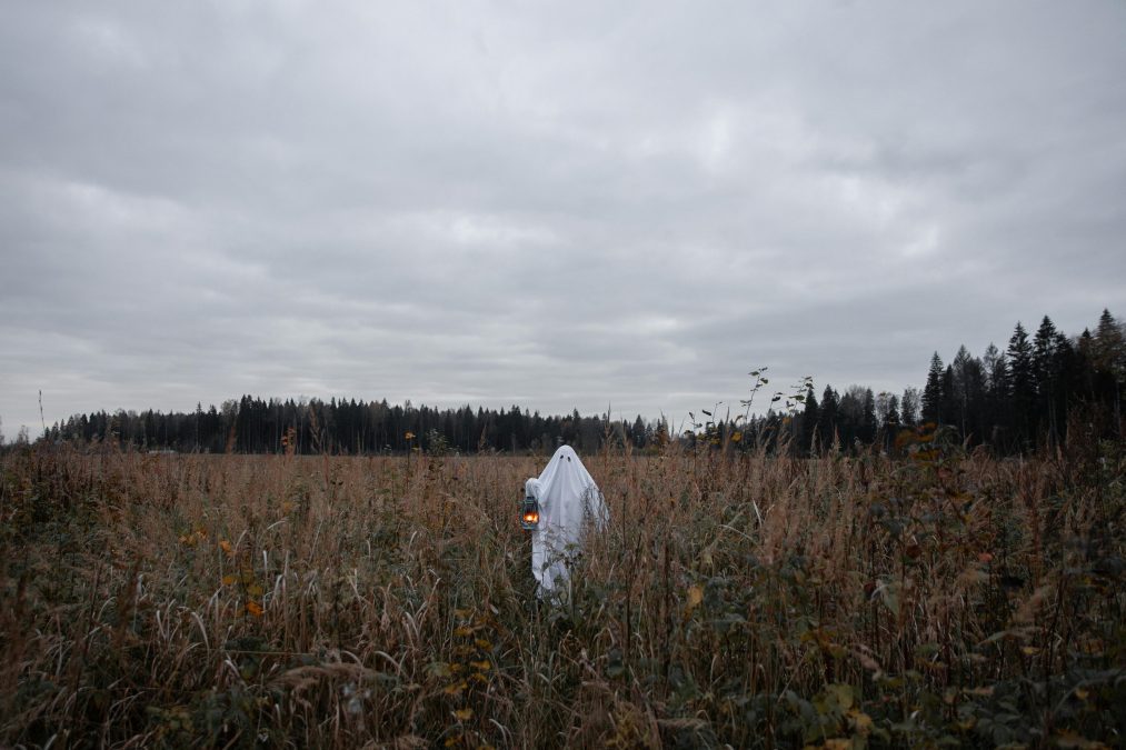 A person dressed like a ghost holds a lantern while standing in an open field. Image used for illustration purposes. PHOTO/Pexels
