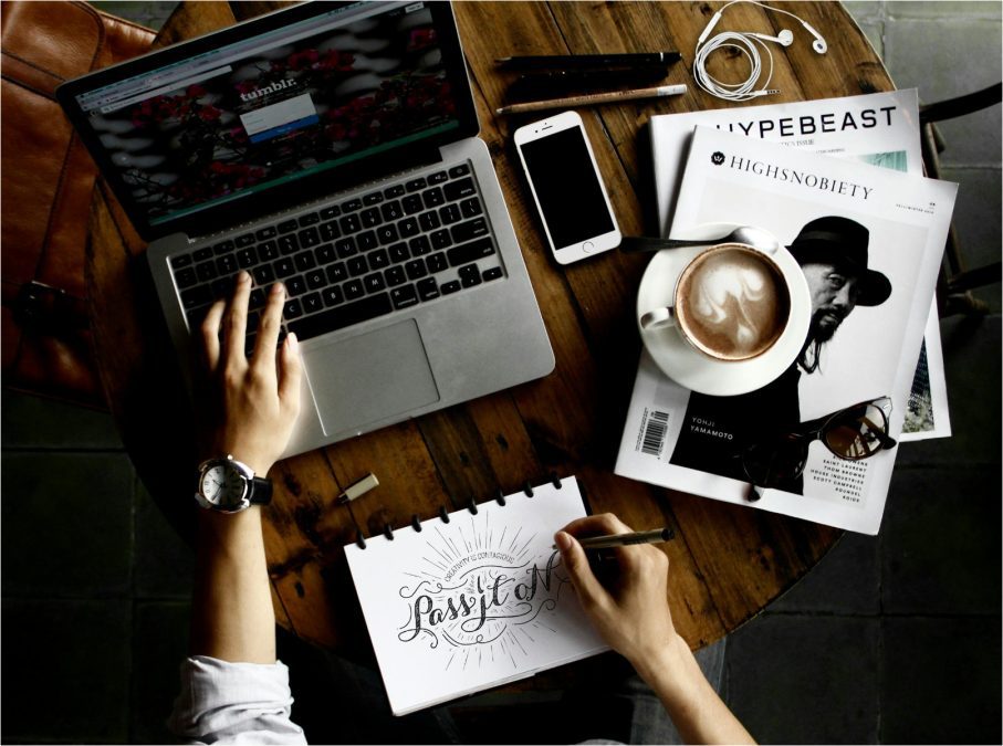 Person sitting facing laptop with sketchpad
