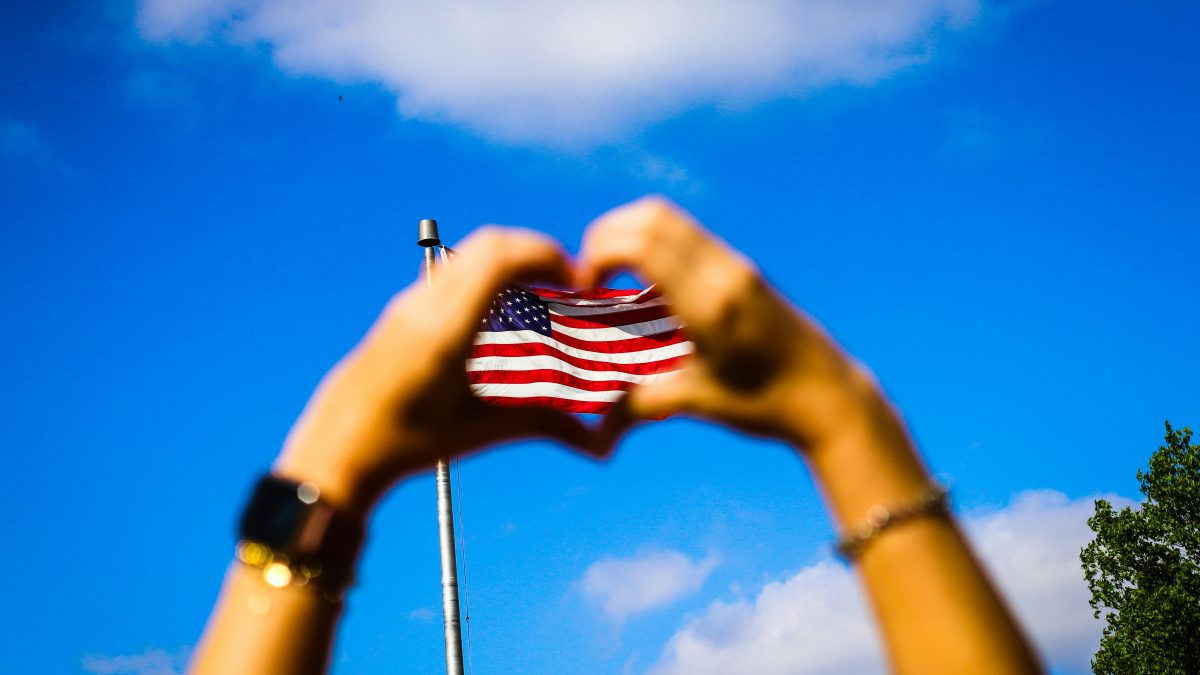 A person forms a heart shape over a US flag. Image used for illustration purposes. PHOTO/Pexels