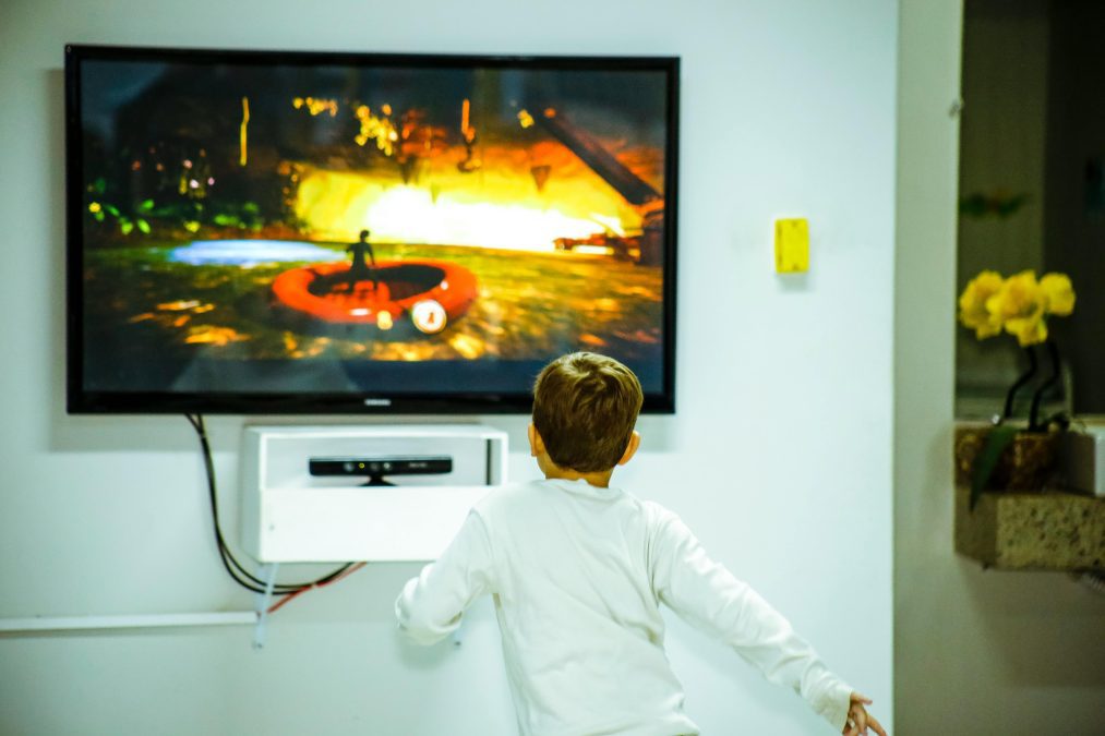 A kid watching a TV mounted on the wall. PHOTO/Pexels