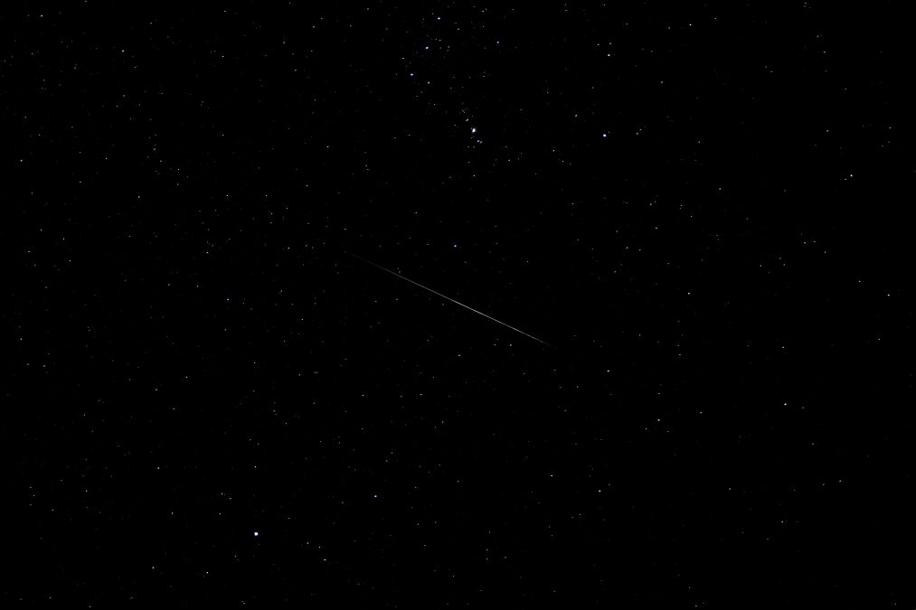 A meteor streaks across the night sky during the Geminids meteor shower.