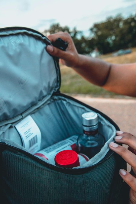 Person opening a backpack with small bottles inside. Image used for illustration purposes. PHOTO/Pexels