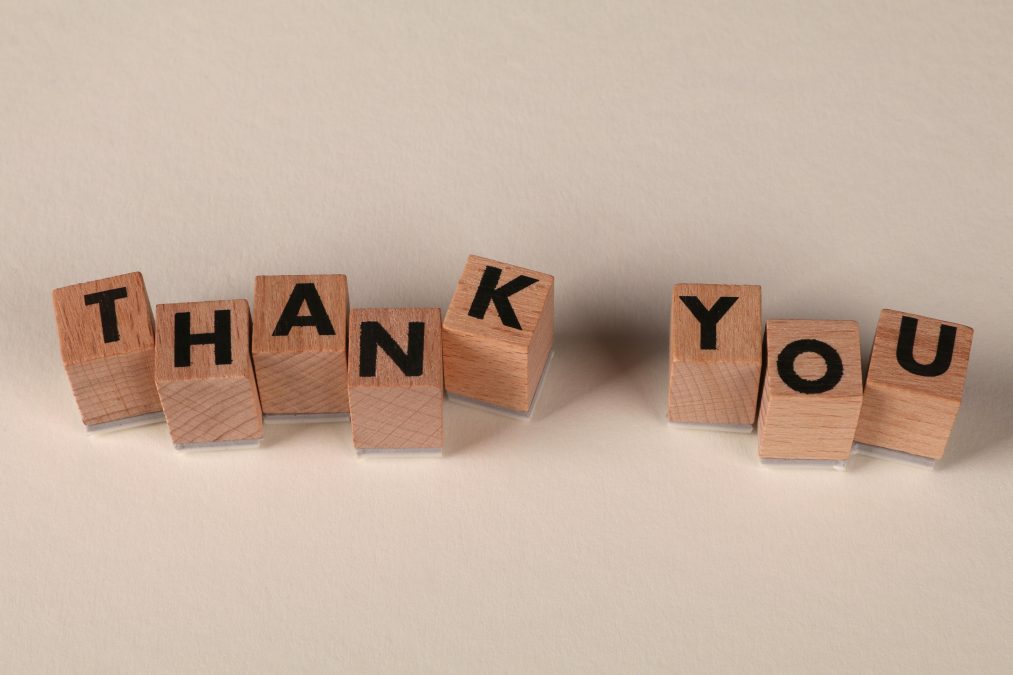 Wooden letter blocks arranged to spell “THANK YOU” on a plain light background. PHOTO/Pexels