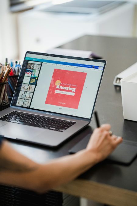 A person works on a laptop at a desk, using a stylus and drawing tablet while designing a colourful web page layout on the screen PHOTO/Pexels