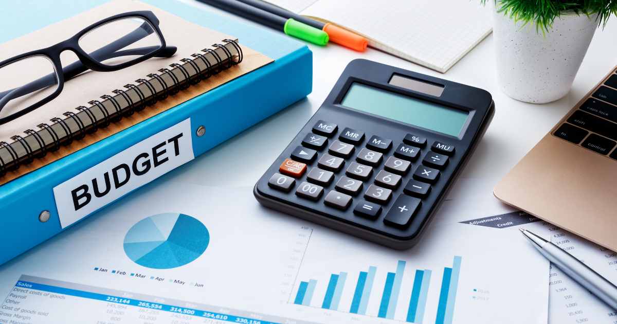 A clean and organised workspace featuring a budget binder, calculator, financial charts, and a laptop on a desk. PHOTO/Pexels