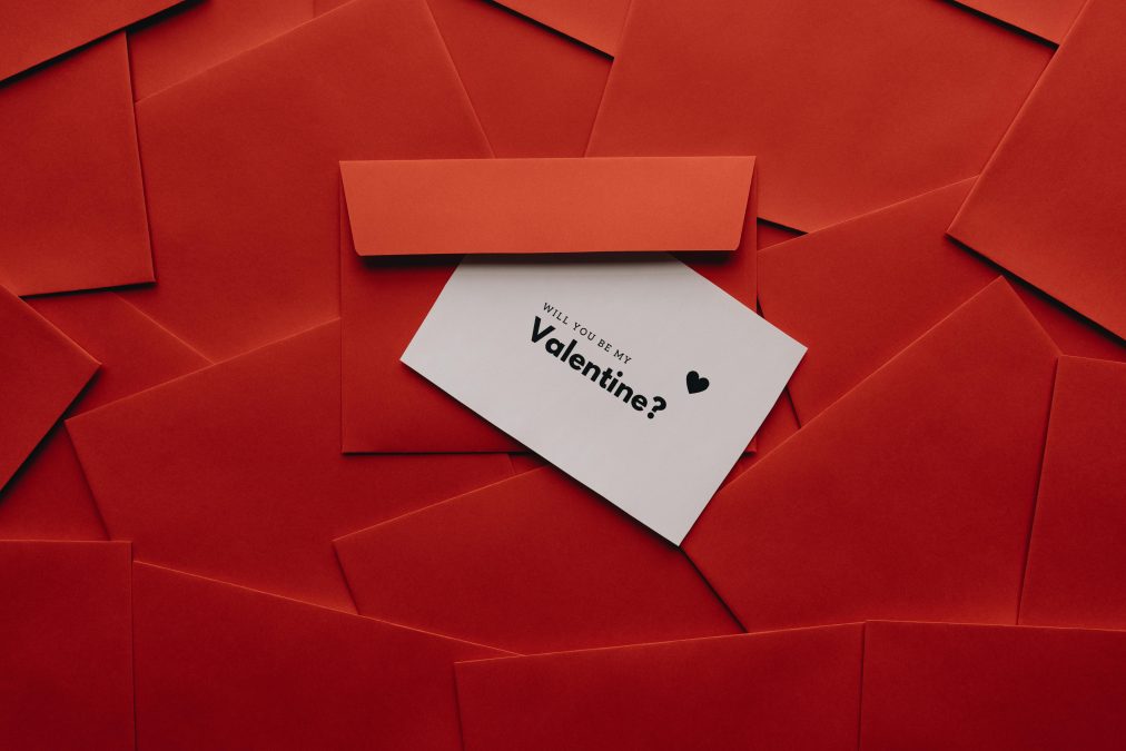 A romantic Valentine’s Day concept featuring a white card that reads Will you be my Valentine placed inside a red envelope surrounded by multiple red envelopes. PHOTO/Pexels