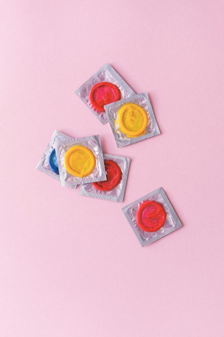 Multicoloured condoms heaped ona  pink background. Image used for illustration purposes. PHOTO/Pexels
