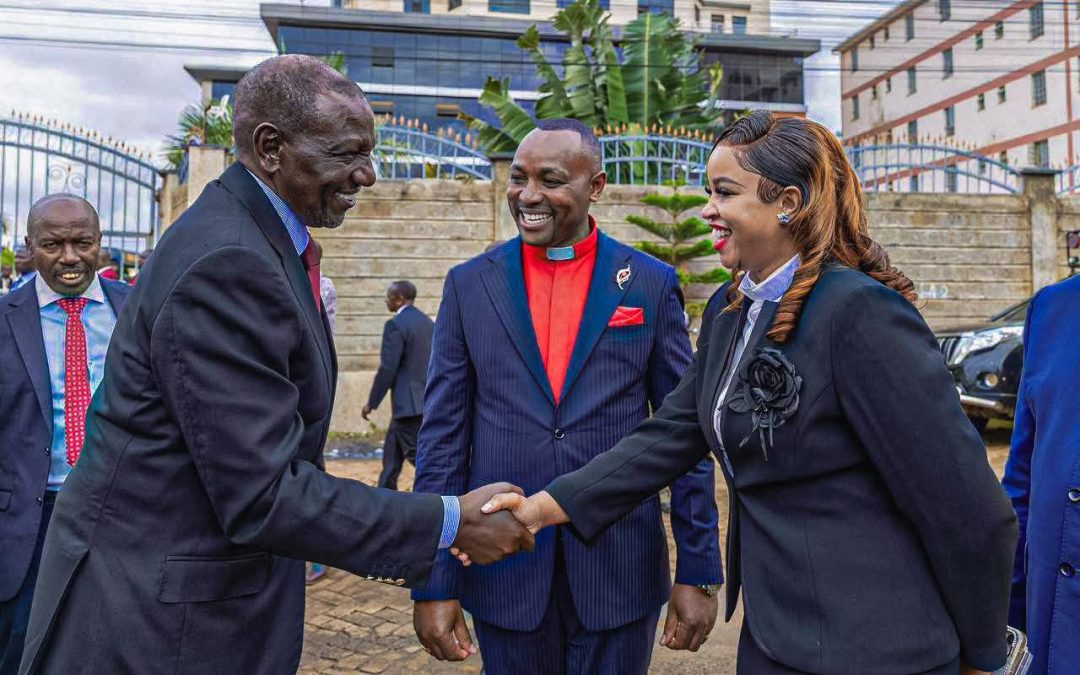 President William Ruto greets Bishop Ben Kiengei's wife, Reverend Joy, as Kiengei poses by. PHOTO/https://www.facebook.com/williamsamoei