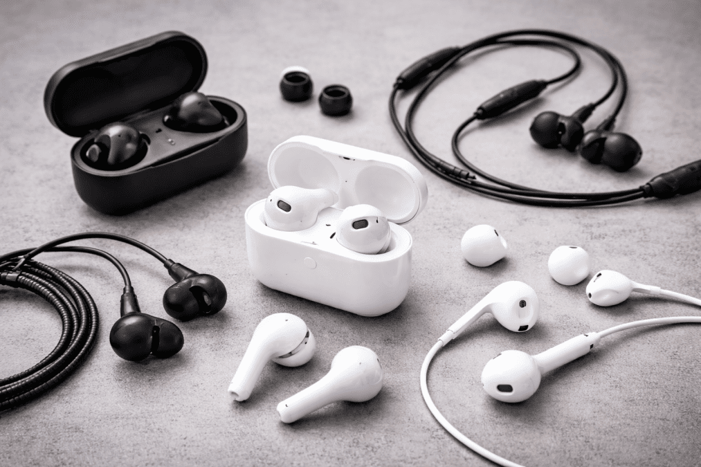 A collection of modern wireless earbuds and wired earphones arranged on a surface, showcasing different audio listening devices for music and calls. PHOTO/AI