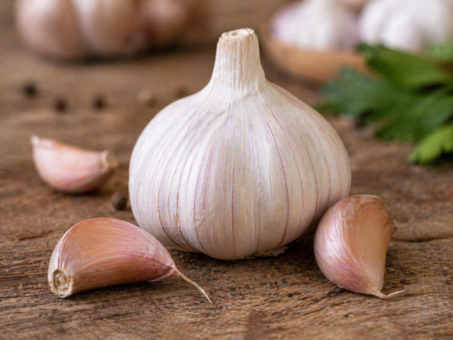 Fresh garlic bulb with peeled cloves placed on a rustic wooden table. PHOTO/Photo generated by AI