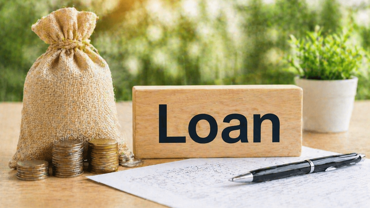 Wooden block labeled Loan placed beside coins, a money bag and paperwork on a table, showing a simple everyday borrowing and finance concept. PHOTO/Photo generated by AI