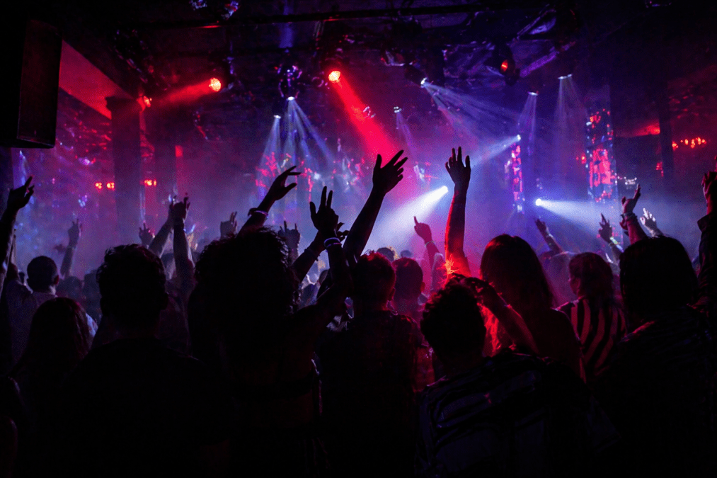 People enjoying themselves in a dark nightclub with colorful lights and faces hidden in silhouette. PHOTO/Photo generated by AI