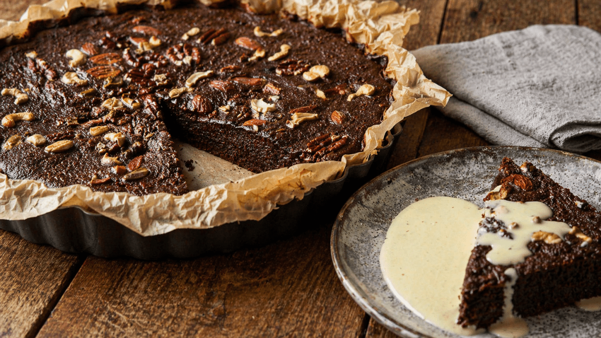 A rich chocolate cake topped with crunchy nuts, beautifully served with a smooth creamy drizzle for a warm and indulgent treat. PHOTO/Photo generated by AI