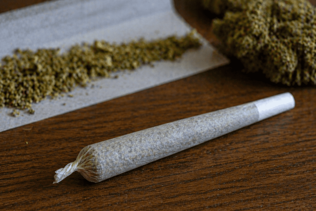 Rolled bhang joint placed on a wooden table beside loose cannabis and rolling paper. PHOTO/Photo generated by AI
