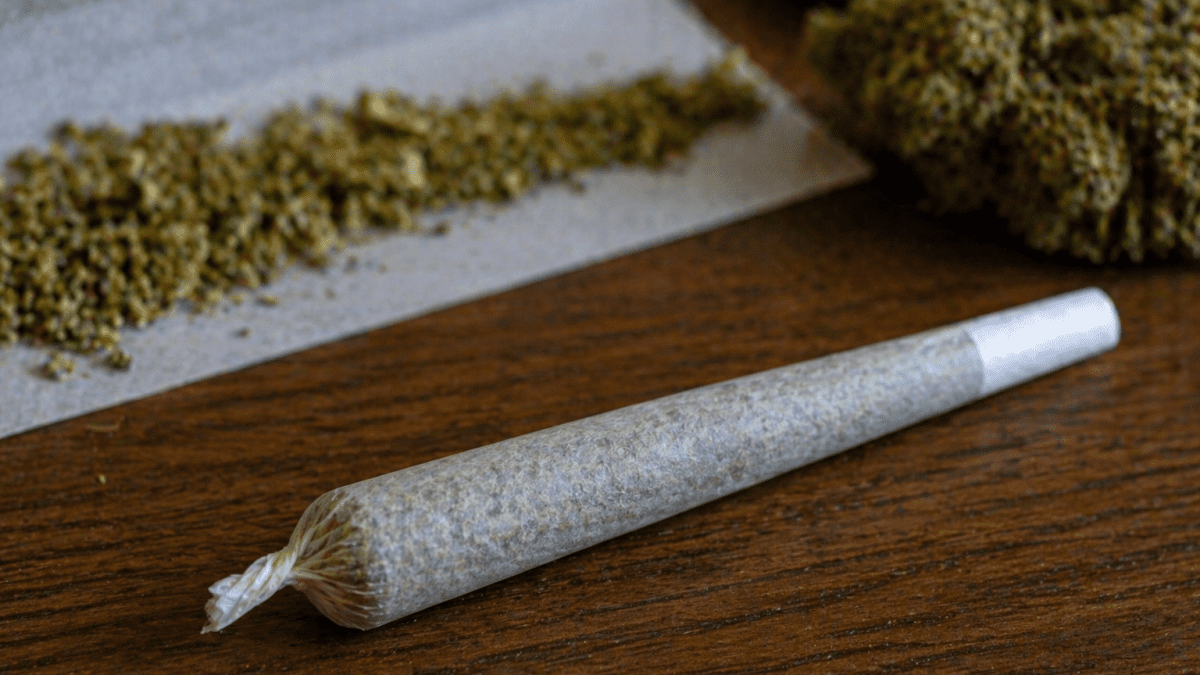 Rolled bhang joint placed on a wooden table beside loose cannabis and rolling paper. PHOTO/Photo generated by AI