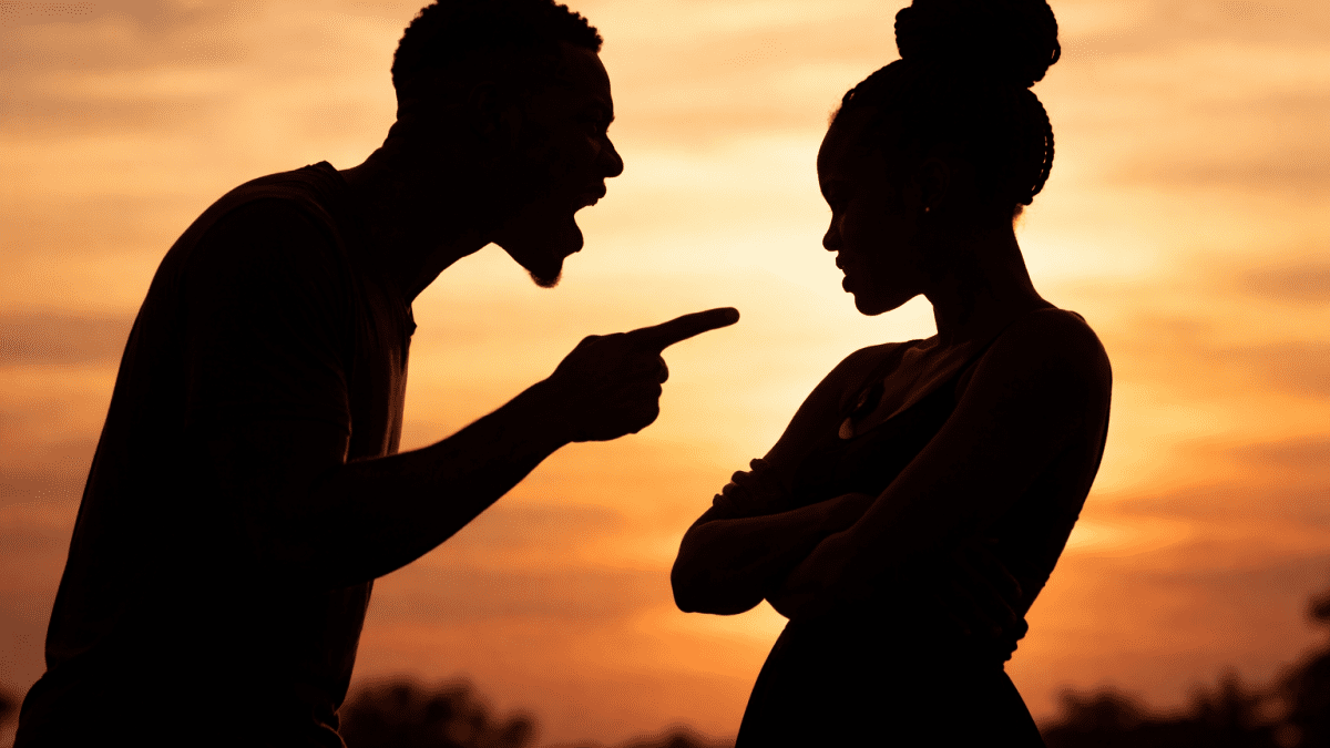 Silhouette of couple in tense argument as man talks at his partner. PHOTO/AI