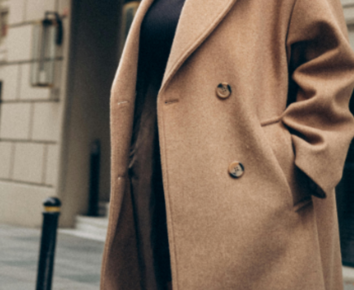 A woman in a brown coat is posing for a photo in the city. PHOTO/AI