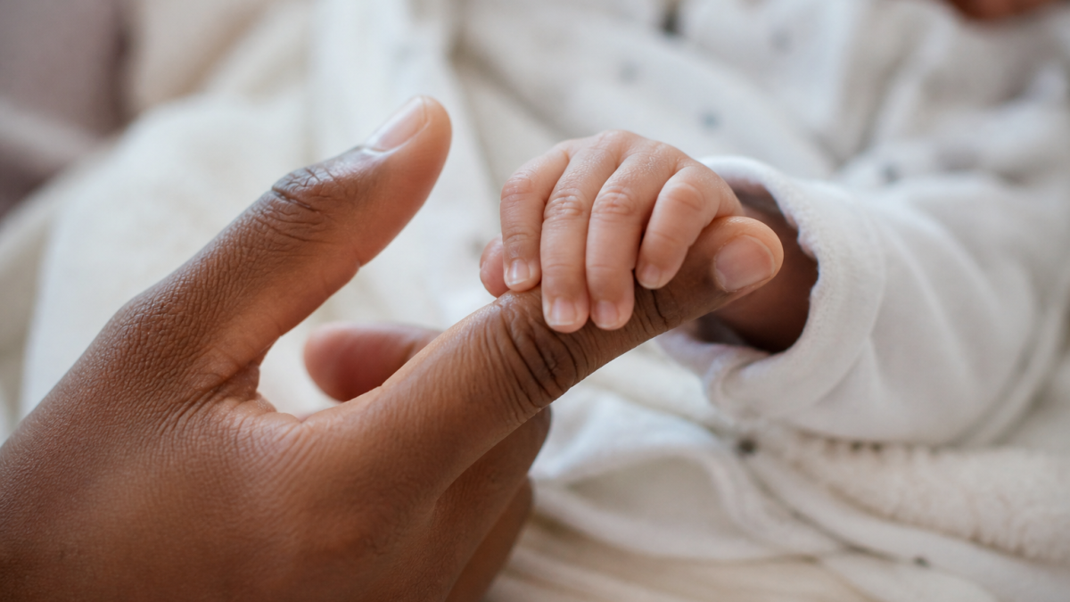 Generated image of a newborn holding someone's index finger. PHOTO/AI