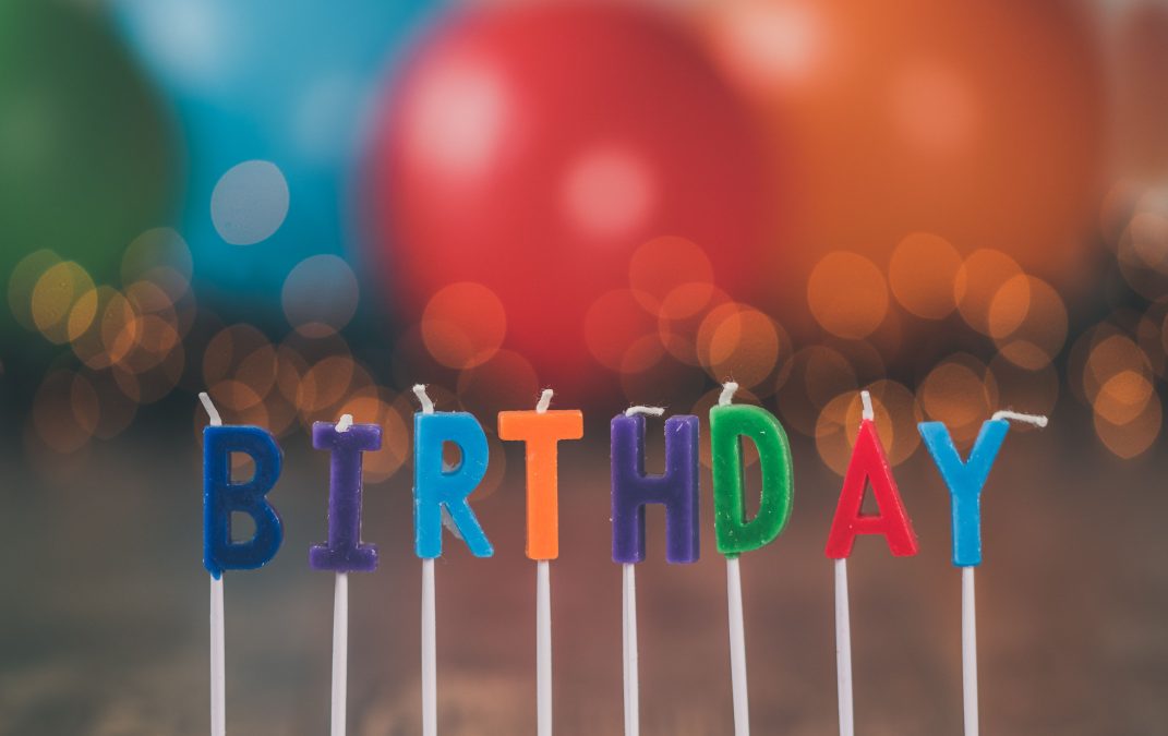 Vibrant birthday candles spelling "BIRTHDAY" against a festive, blurred background