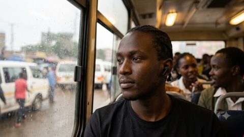 A focused commuter enjoys silence inside a chaotic matatu.