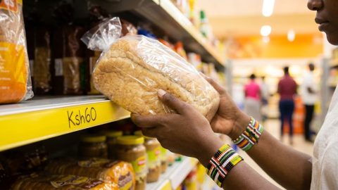 A shopper's hands hold a loaf of bread above a yellow price tag reading Ksh60.