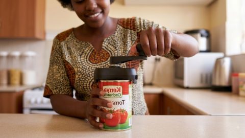 Hands effortlessly operate a left-handed can opener on a tin of tomatoes.
