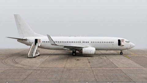 A white airplane sits on foggy tarmac.