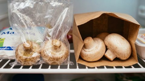 Wet, slimy mushrooms in plastic contrast sharply with fresh mushrooms in paper.