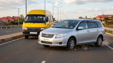 A car emergency braking on a highway to avoid a matatu.