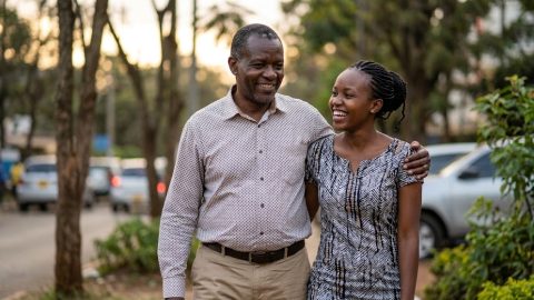 A couple with an age gap smiling while walking outdoors.