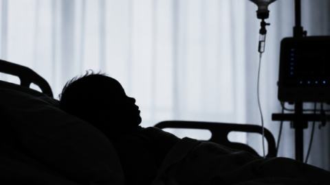 A silhouette of a child lying in a hospital bed.