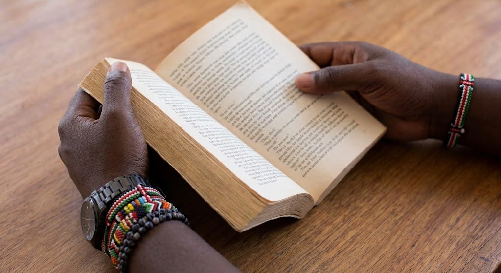 Hands holding an open fiction book.